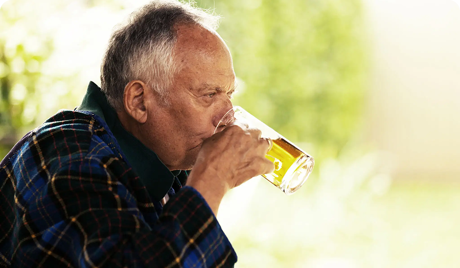 Elderly man drinking from a glass.